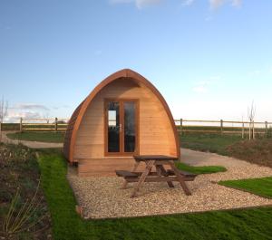 a small wooden cabin with a picnic table in the grass at Mallow Glamping Pod in Cheltenham