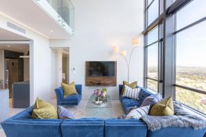uma sala de estar com um sofá azul e janelas em Masingita Towers Penthouse em Joanesburgo