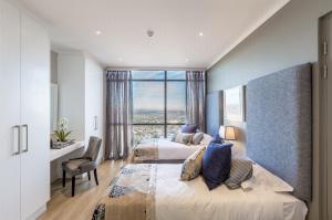 1 dormitorio con 2 camas, escritorio y ventana en Masingita Towers Penthouse en Johannesburgo