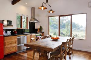 a kitchen with a wooden table with chairs and a large window at Adventure Bay Retreat Bruny Island in Adventure Bay