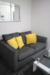 ein graues Sofa mit gelben Kissen im Wohnzimmer in der Unterkunft Halifax House, Studio Apartment 213 in Halifax