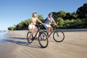 two people riding bikes on the beach at Martinique On Macrossan in Port Douglas