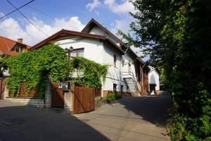 uma casa branca com um portão de madeira e uma entrada em Buda Side em Budakeszi