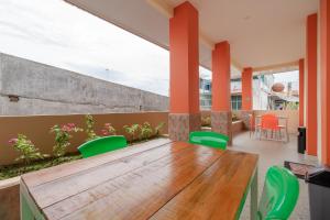 a patio with a wooden table and green chairs at RedDoorz Syariah @ Panglima Polem Aceh in Banda Aceh