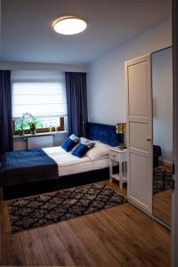 sypialnia z łóżkiem z niebieskimi poduszkami i oknem w obiekcie Apartamenty Silva Hel w mieście Hel