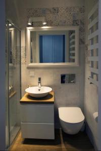 a bathroom with a sink and a toilet and a mirror at Apartamenty Silva Hel in Hel