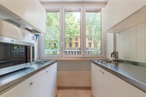 eine Küche mit weißen Schränken und einem großen Fenster in der Unterkunft Nina Casetta De Trastevere in Rom