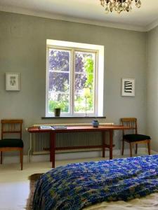 a bedroom with a bed and a desk in front of a window at Liv på Österlen Bed&Breakfast in Sandby