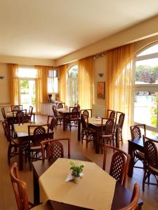 a restaurant with tables and chairs and windows at Hotel Kalamitsi Apartments in Preveza