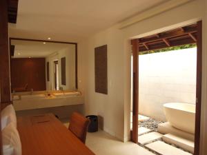 a bathroom with a tub and a sink and a table at The Menjangan by LifestyleRetreats in Banyuwedang