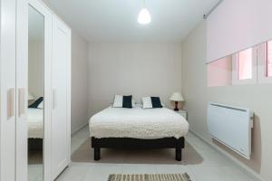 a white bedroom with a bed and a mirror at Appartement Marie in Strasbourg