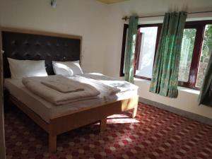 a bedroom with a bed in a room with windows at Hotel Rezang-La in Leh