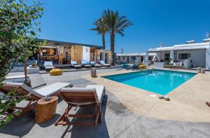 a swimming pool with lounge chairs and a house at White and Grey in Mikonos