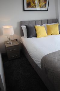 ハリファックスにあるHalifax House, Studio Apartment 214のベッドルーム1室(黄色い枕とランプ付きのベッド1台付)