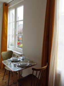 Una mesa con platos y vasos y una ventana. en l'Otis et le Titouan Saint-Sauveur, en Dinan