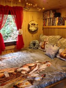 a bedroom with a bed with a painting on it at 'Morris' the shepherd's hut with woodland hot tub in Carmarthen