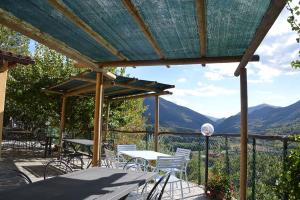 un patio con mesas y sillas con montañas en el fondo en ristorantino il Sovrano BeB, en SantʼAnatolia di Narco