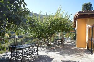 un patio con mesas y sillas bajo un árbol en ristorantino il Sovrano BeB, en SantʼAnatolia di Narco