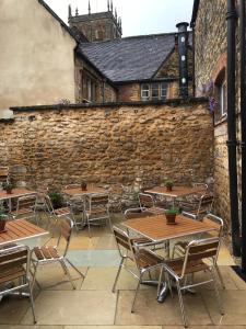 a patio with tables and chairs in front of a brick wall at The Cross Keys Sherborne in Sherborne