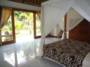 a bedroom with a bed with a black and white canopy at Suka's House Bed & Breakfast in Ubud
