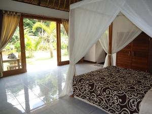 1 dormitorio con 1 cama con dosel blanco y negro en Suka's House Bed & Breakfast, en Ubud