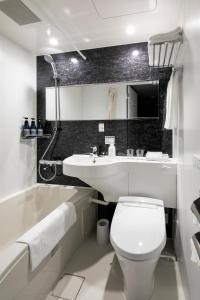 a bathroom with a toilet and a sink and a tub at Act Hotel Shibuya in Tokyo