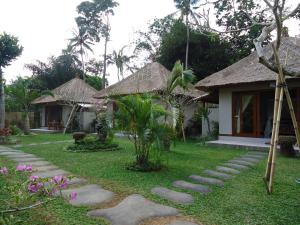 a garden with a path leading to a house at Suka's House Bed & Breakfast in Ubud