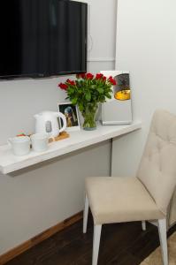 ein weißes Regal mit einer Vase aus Blumen und einem Stuhl in der Unterkunft Serendipity in Smederevo