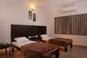 a hotel room with two beds and a window at Vinay Residency in Sindhnūr