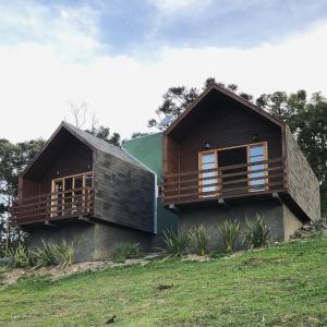 une maison sur une colline herbeuse avec deux ponts dans l'établissement Refúgio da Montanha, à Urubici