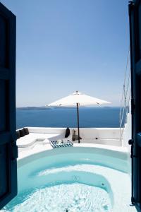 a jacuzzi tub with an umbrella and the ocean at Oia's Secret in Oia