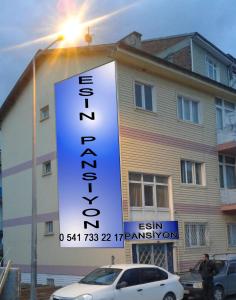 a sign in front of a building with a car at Esin Pansiyon in Tokat