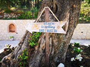 a sign that says beach is calling but i must gut at Nikoli Apartments in Benitses