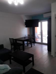 een woonkamer met een tafel, stoelen en een televisie bij Apartamento Algemsí Cullera in Cullera +2 foto's