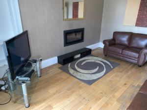 a living room with a television and a couch at The Village Tavern Apartment in Larkhall