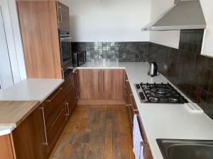 a kitchen with white counter tops and wooden cabinets at The Village Tavern Apartment in Larkhall