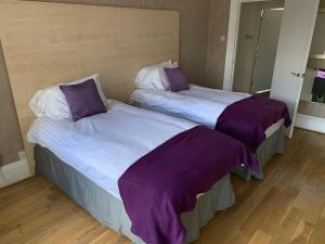 two beds sitting next to each other in a room at The Village Tavern Apartment in Larkhall