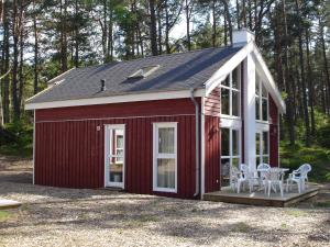 einen roten Schuppen mit einer Veranda und weißen Stühlen in der Unterkunft Strandhaus Deichkrone in Baabe