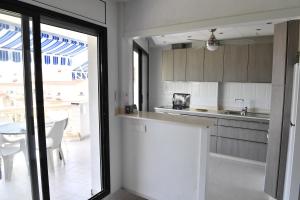 kuchnia z białymi szafkami, stołem i oknem w obiekcie Appartement exceptionnel confortable bord de mer w mieście Sant Carles de la Ràpita