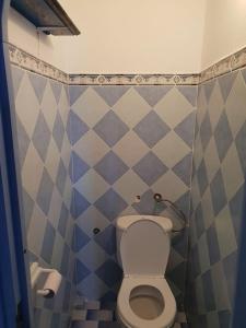 uma casa de banho com WC e azulejos azuis e brancos em Hotel Ouarzazate em Chefchaouene