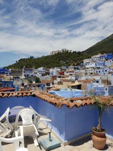a balcony with two chairs and a swimming pool on a city at Hotel Ouarzazate in Chefchaouene +37 photos