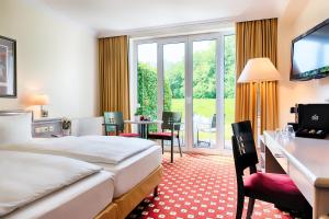 a hotel room with a bed and a desk and a television at Welcome Hotel Bad Arolsen in Bad Arolsen