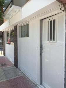 een witte garagedeur aan de zijkant van een gebouw bij Loutraki Hostel in Loutraki