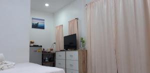 une chambre avec un lit, une télévision et des rideaux dans l'établissement บ้านอิงธารา โฮมสเตย์ ศาลายา Baan ing tara homestay salaya, à Salaya