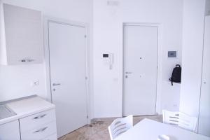 cocina blanca con armarios blancos, mesa y sillas en Clambè en Palermo