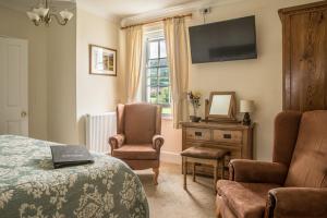 een slaapkamer met een bed, een stoel en een televisie bij Hardwick Farm in Abergavenny