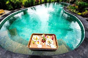 a tray of food sitting on a table in a pool at Puri Kobot in Ubud
