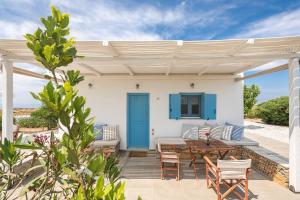 a white house with a blue door and a wooden table at Celestial Kythnos in Kithnos