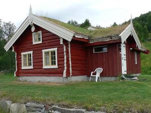 ein rotes Haus mit einem Stuhl davor in der Unterkunft Gamlestugu hytte in Ål