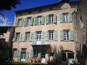 un grand bâtiment avec volets verts dans l'établissement La Résidence Chambre d'Hotes, à Saint-Antonin